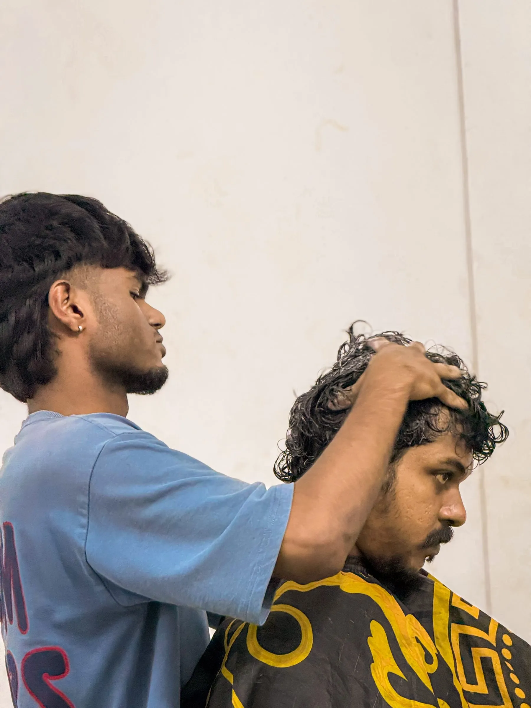 A barber working product into a customer’s wet hair at the chair