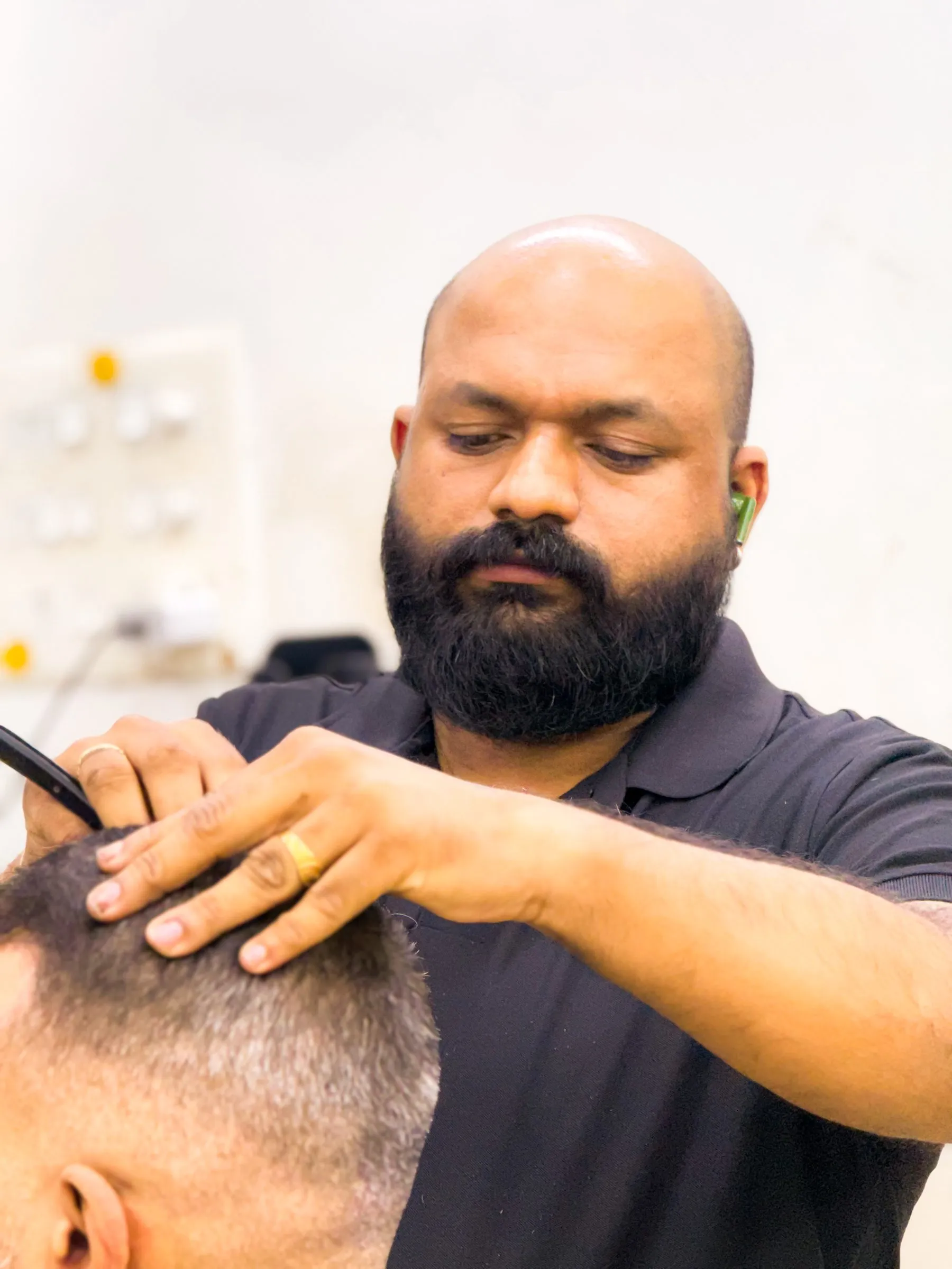 A Gents Camp barber cutting a customer’s hair scissor over comb