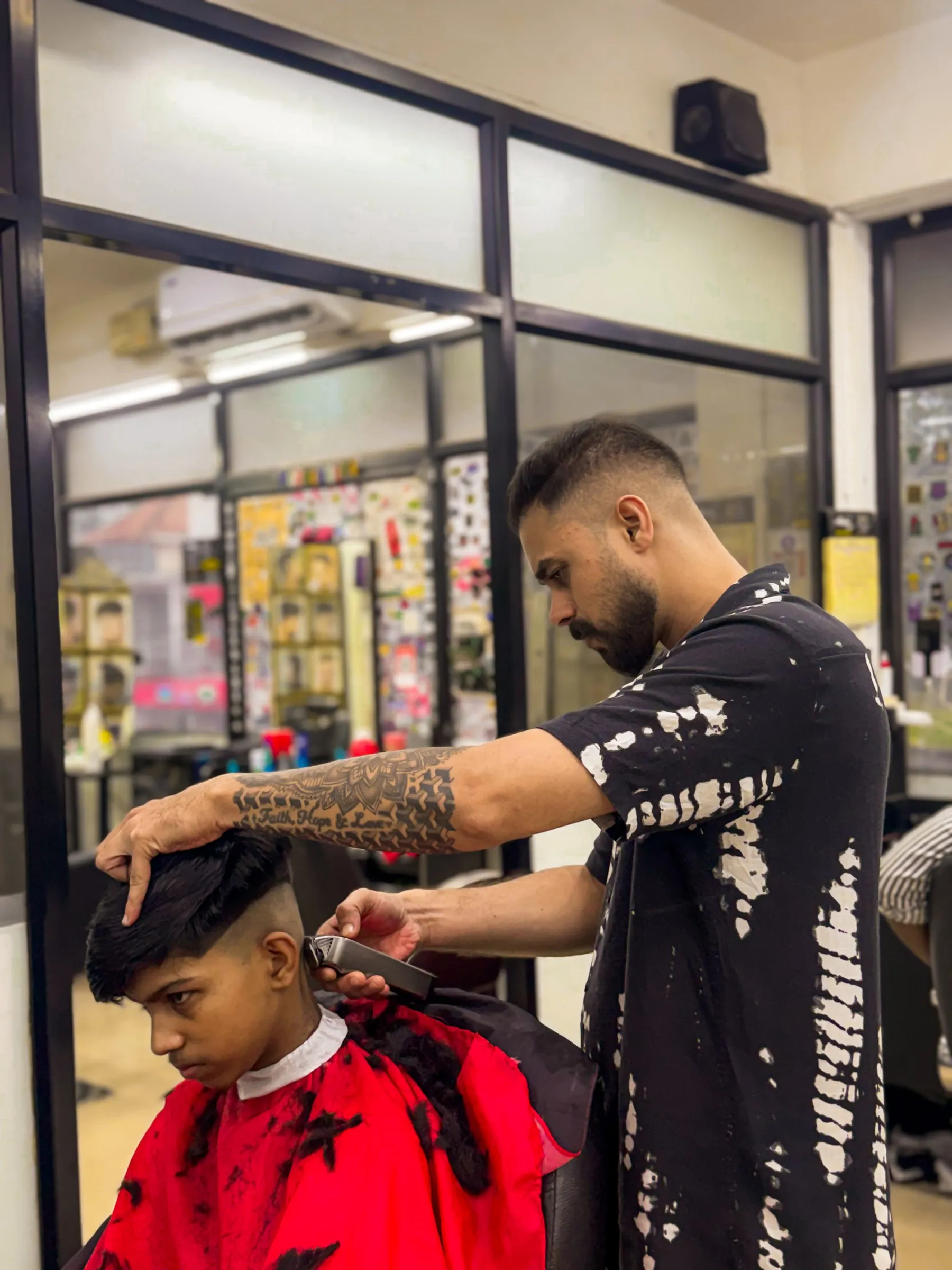 A barber taking a customer’s skin fade down with clippers in the mirrored front room